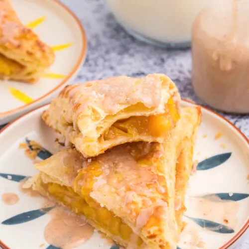 two peach turnovers stacked on plate and sliced open