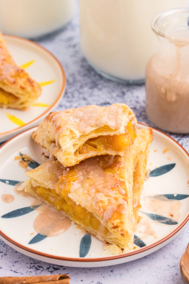 two peach turnovers stacked on plate and sliced open