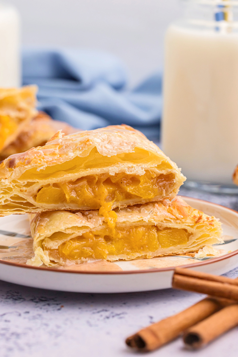 two peach turnovers stacked on plate and sliced open to see inside