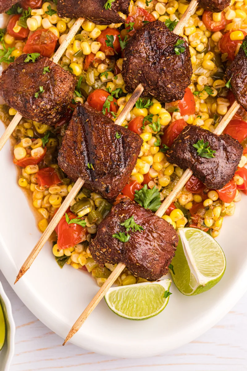 grilled beef kabobs over corn tomato salsa on platter