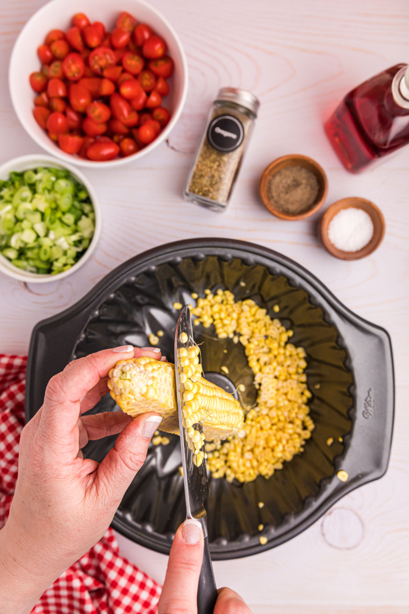 cutting corn off cob into bundt cake pan