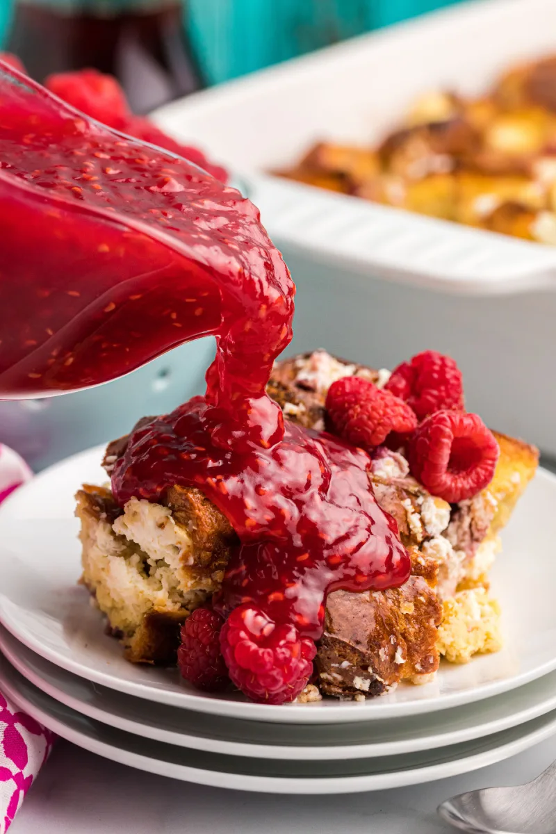 pouring raspberry sauce onto french toast on plate