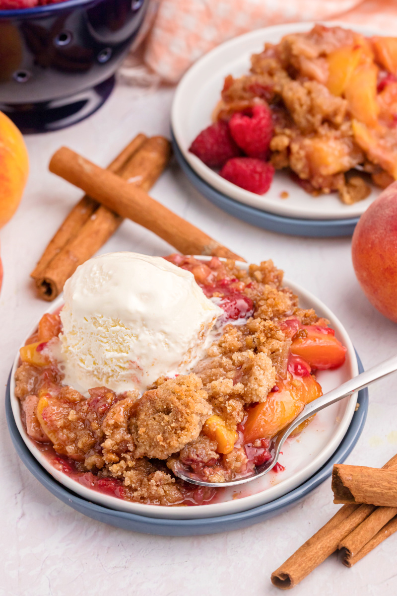 serving of raspberry peach crumble with scoop of vanilla ice cream on top