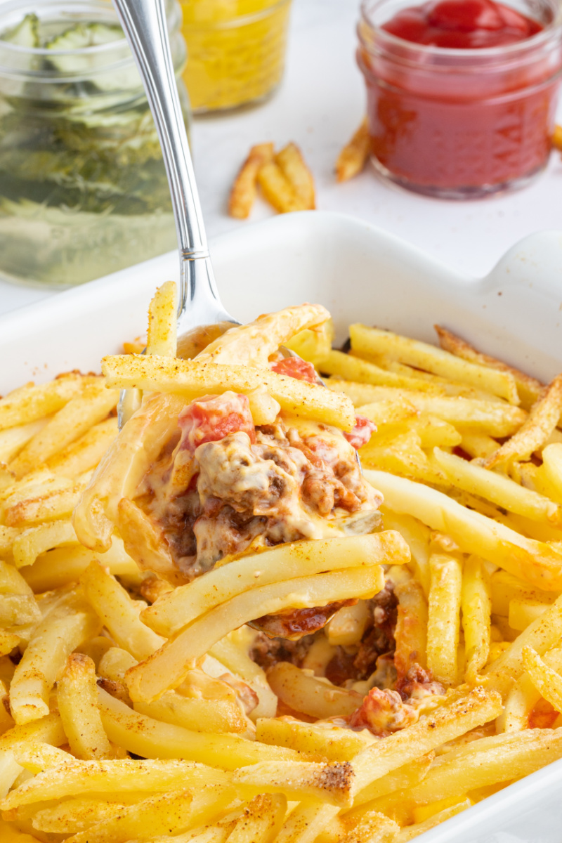 spooning out cheeseburger and fries casserole