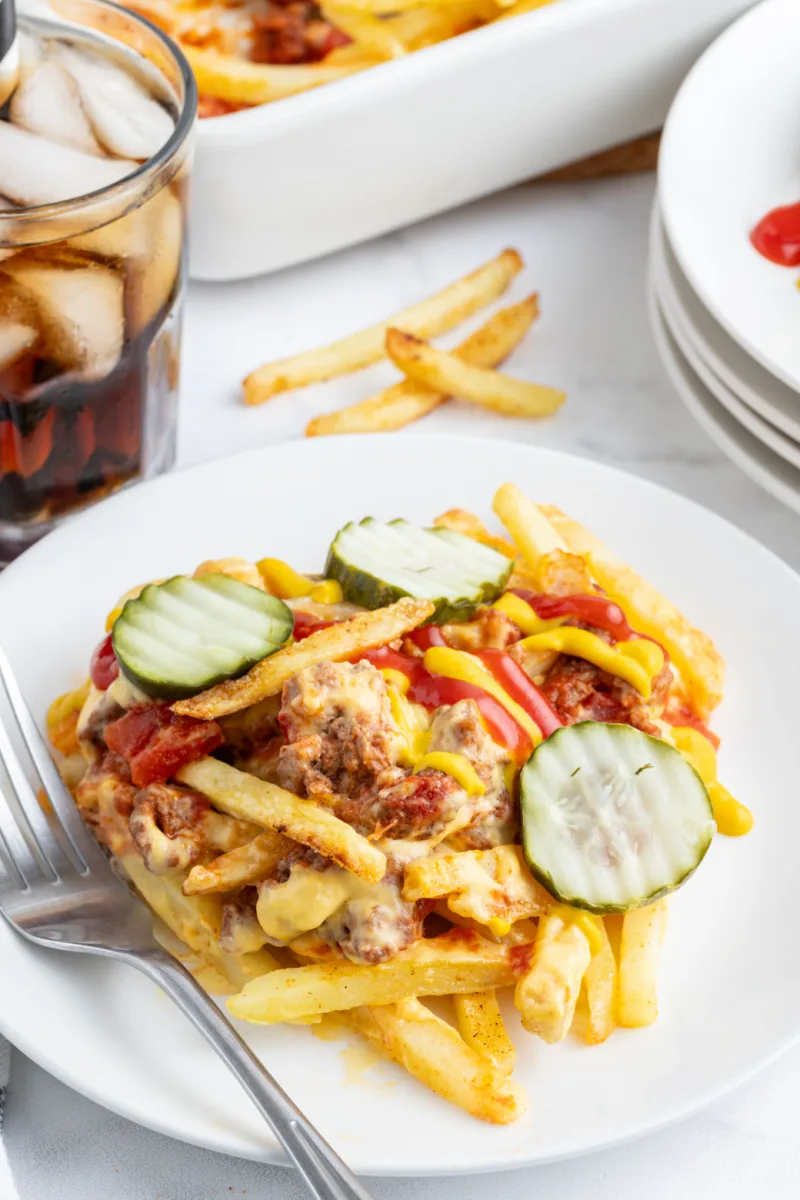 cheeseburger and fries casserole on plate with pickle and ketchup garnish