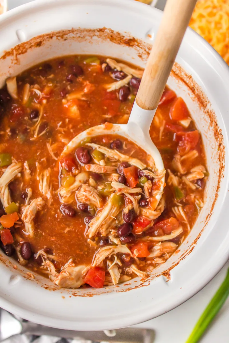 spooning inside slow cooker insert of tortilla soup