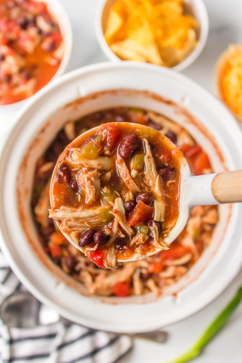 ladle of slow cooker tortilla soup out of slow cooker insert