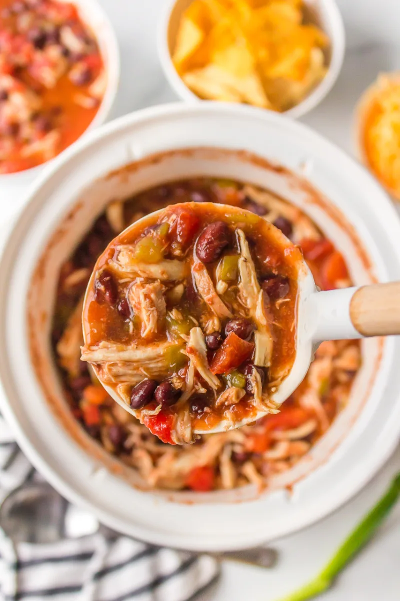 ladle of slow cooker tortilla soup out of slow cooker insert