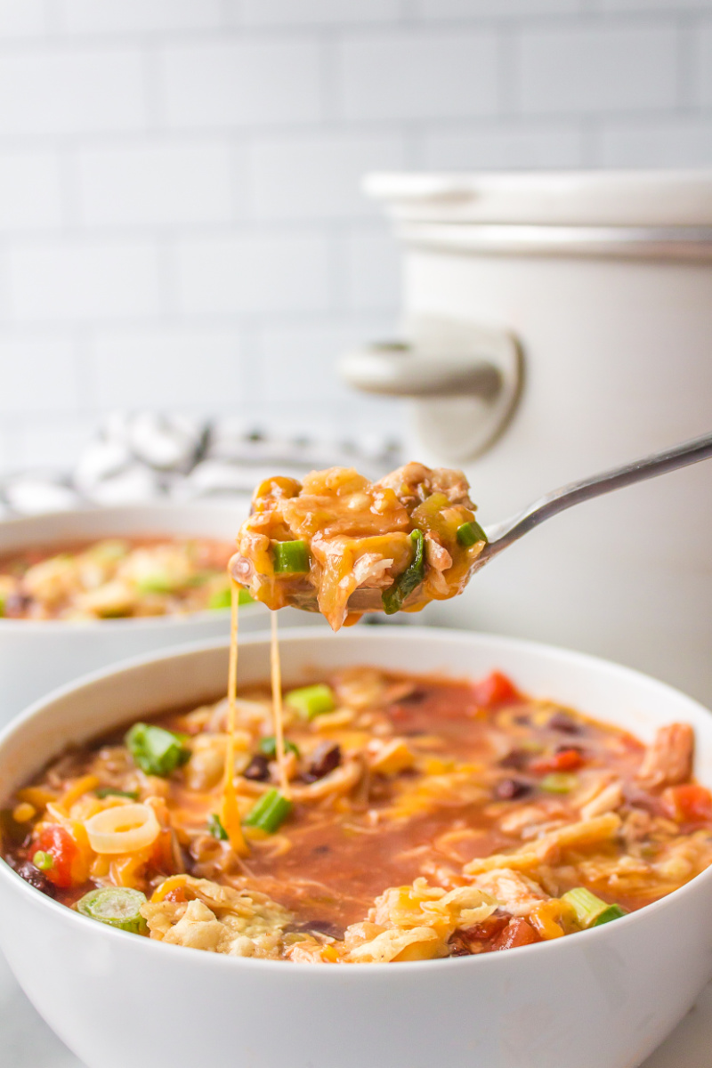 spooning out tortilla soup out of bowl