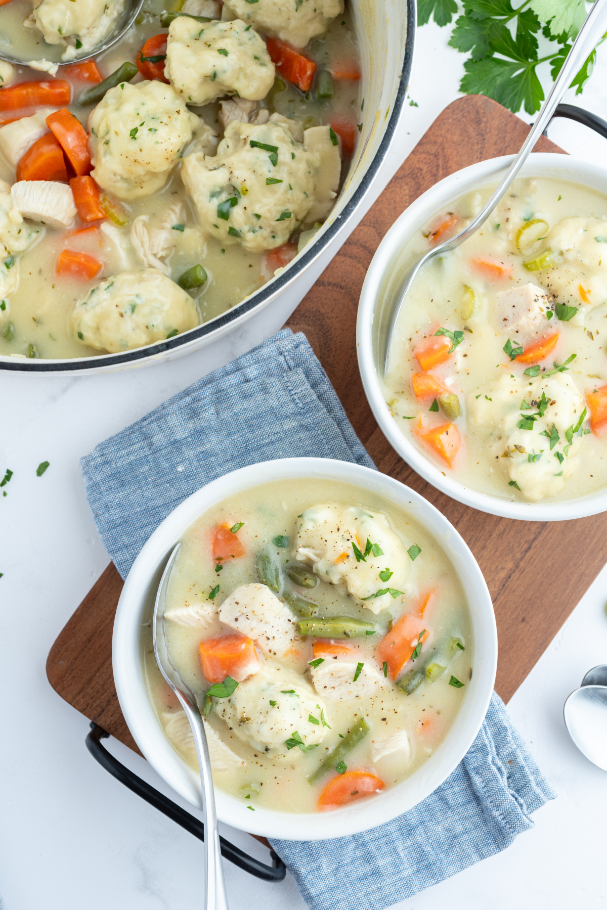 two bowls and a pot of chicken and dumplings