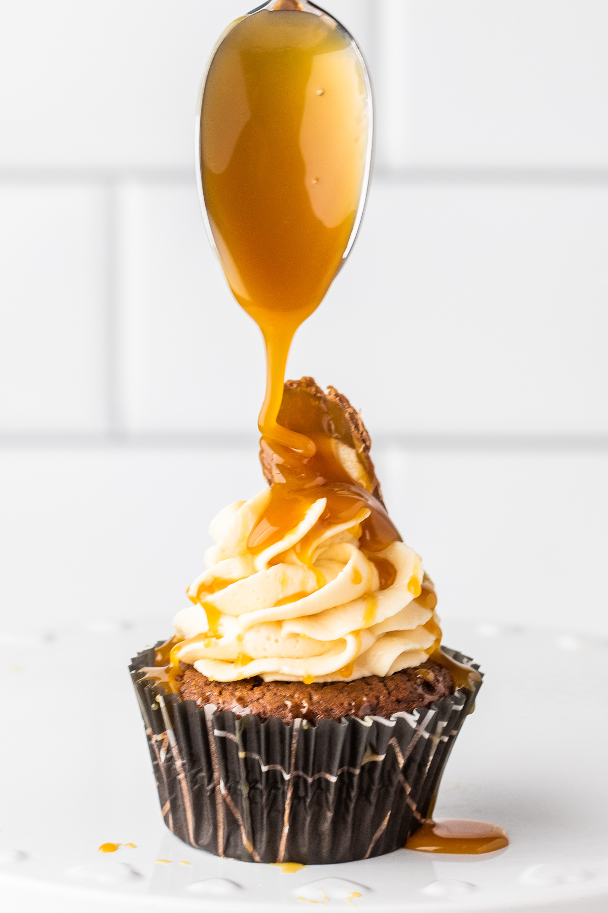 spooning caramel on top of twix bar cupcake