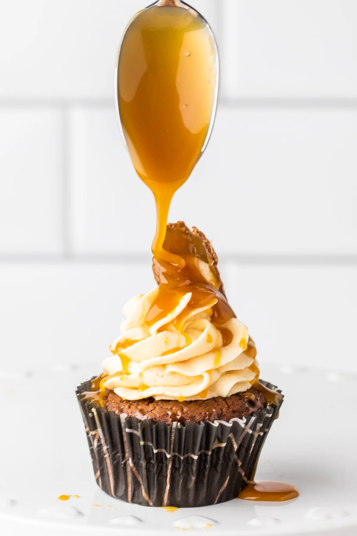 spooning caramel on top of twix bar cupcake