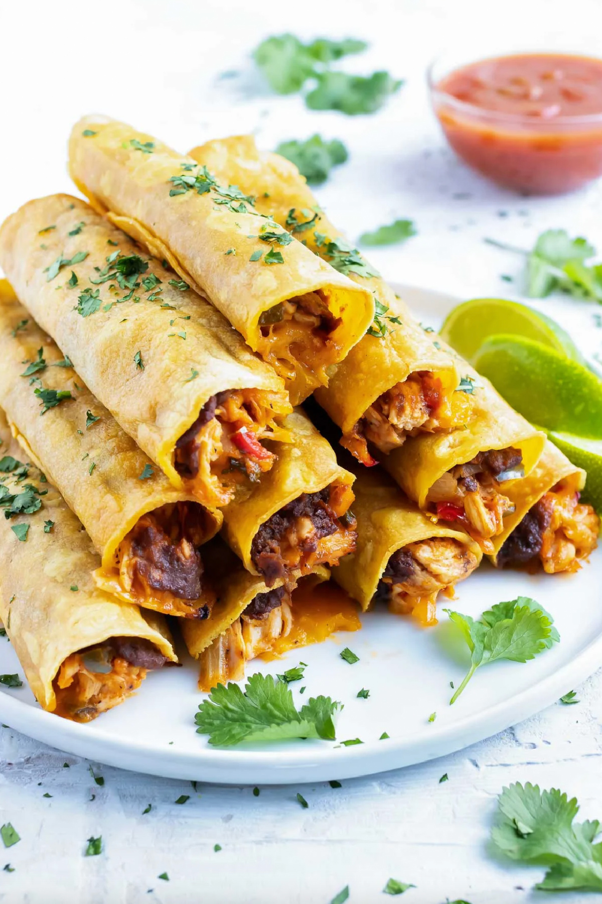 baked cheesy chicken taquitos stacked on platter