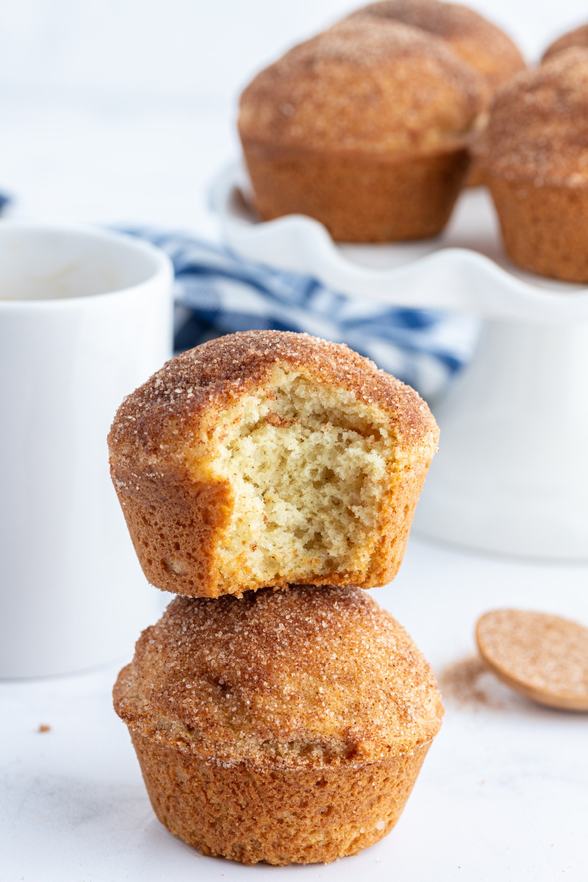 two cinnamon sugar muffins stacked with top one bite taken out