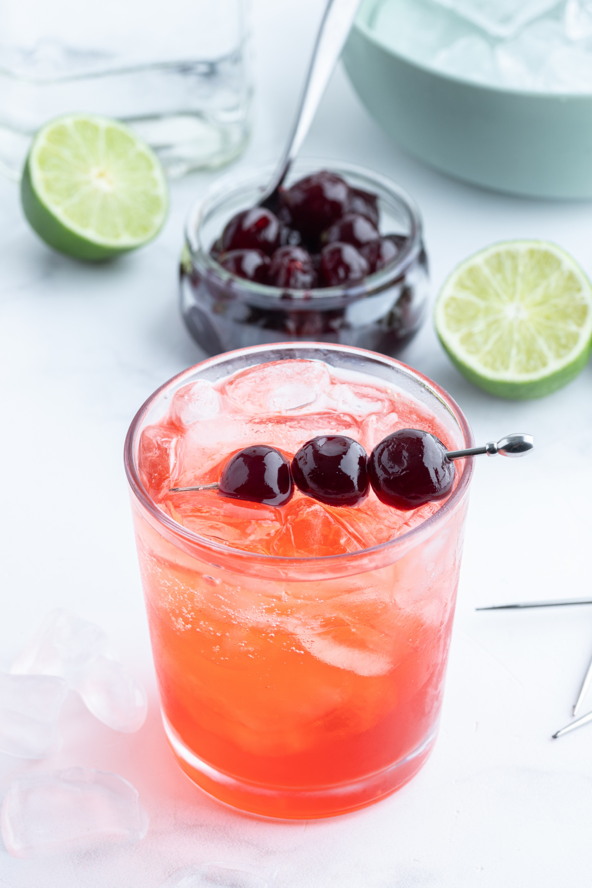 looking down on a tequila shirley temple with a bowl of cherries and cut limes