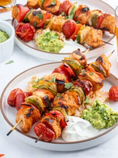 grilled chicken taco kebabs on plate with sour cream and guacamole