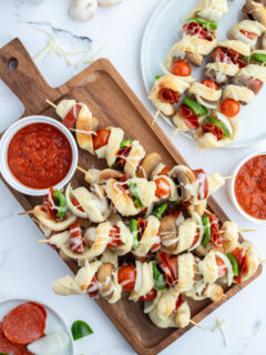 pizza kabobs on cutting board with pizza sauce
