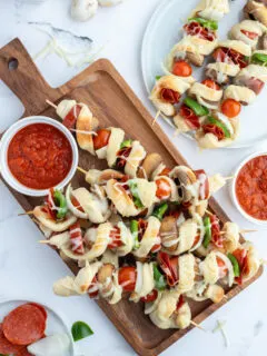 pizza kabobs on cutting board with pizza sauce