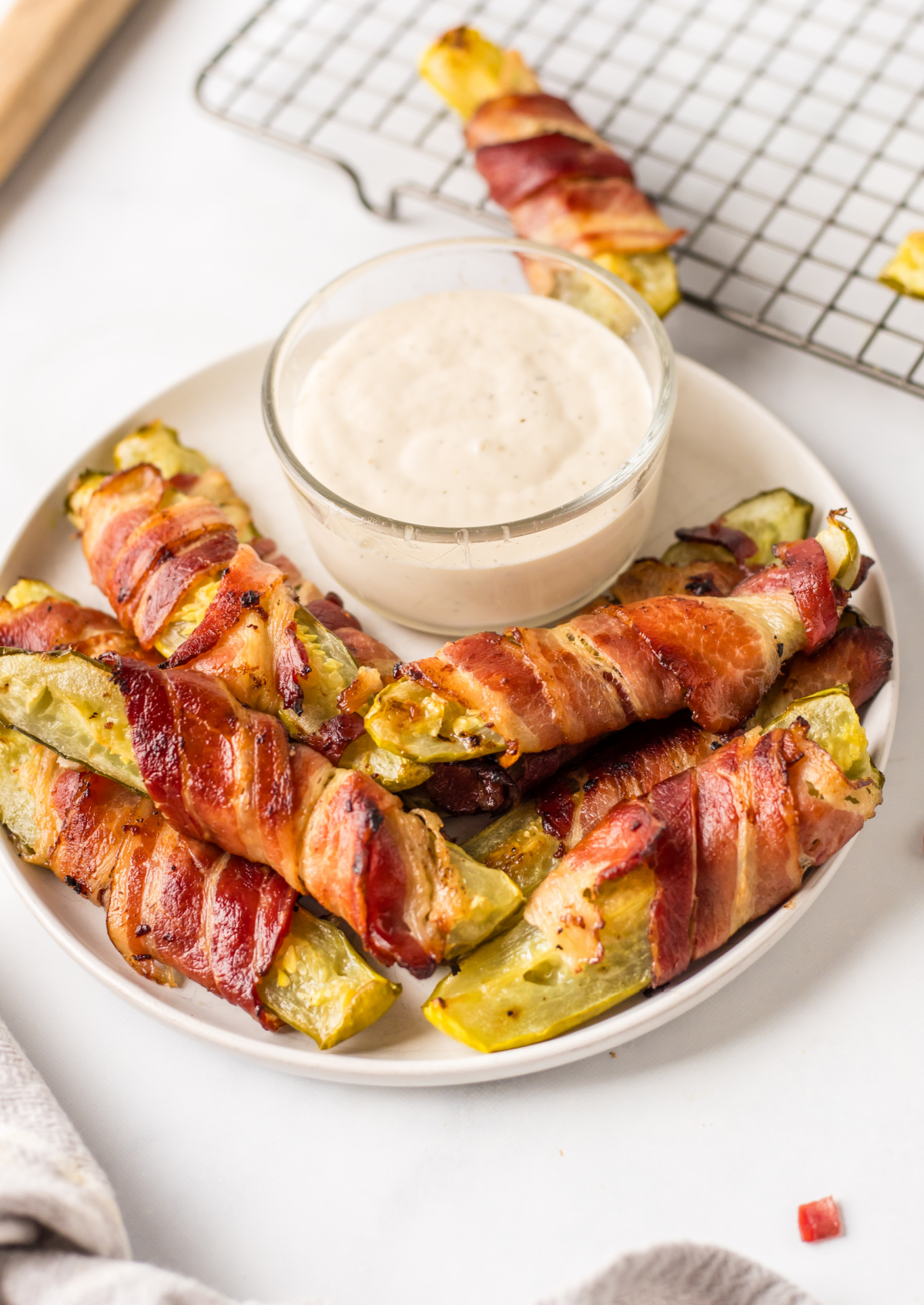 bacon wrapped dill pickles displayed around bowl of ranch dressing