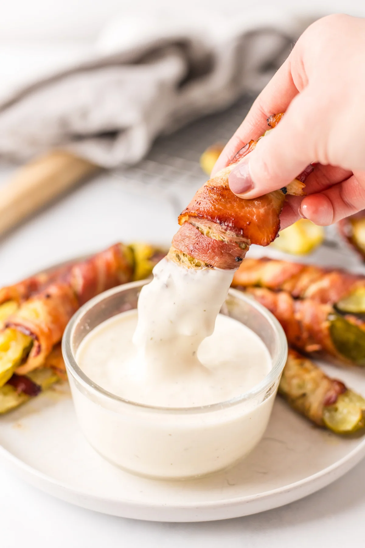 Bacon Wrapped Pickles served with Ranch Dressing recipe on RecipeBoy.com dipping bacon wrapped dill pickle into ranch dressing