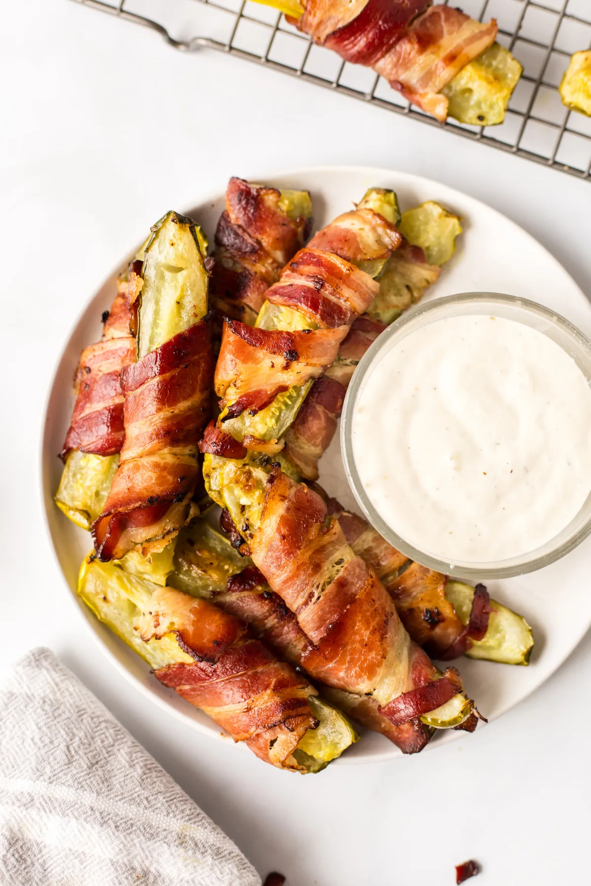 Bacon Wrapped Pickles served with Ranch Dressing recipe on RecipeBoy.com overhead shot of bacon wrapped dill pickles on a plate with ranch dressing