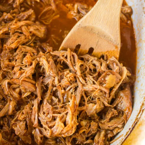 slow cooker texas pulled pork in slow cooker with wooden spoon