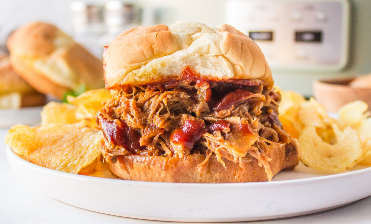 slow cooker texas pulled pork sandwich on plate with potato chips