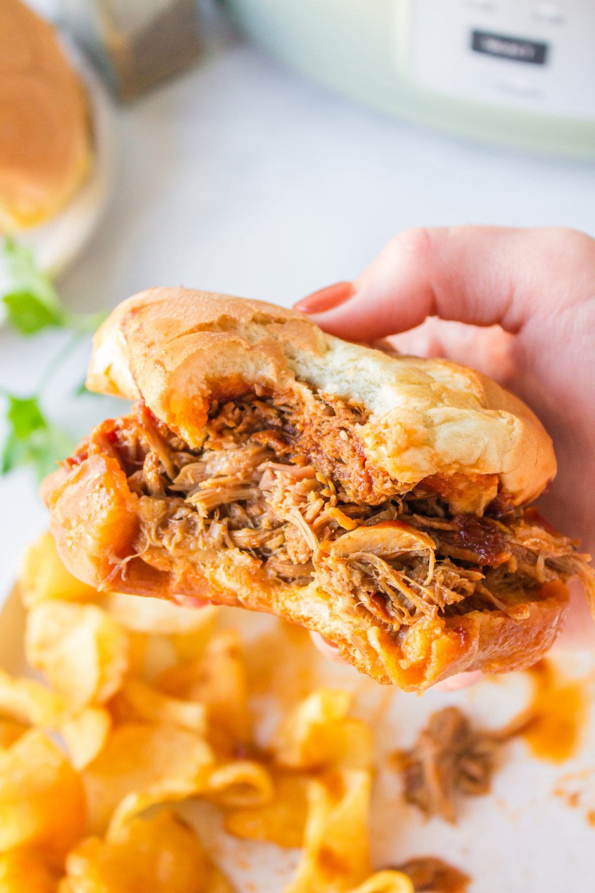 hand holding slow cooker texas pulled pork with bite taken out of it