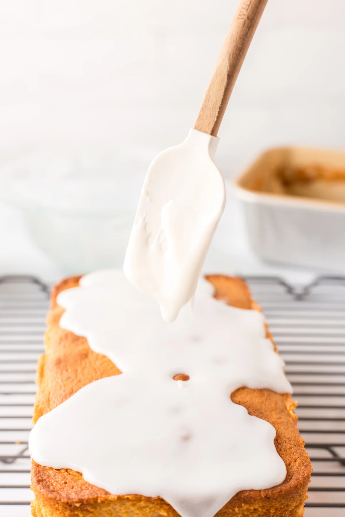 Glazed Lemon Loaf cake recipe from RecipeBoy.com drizzling glaze onto lemon loaf