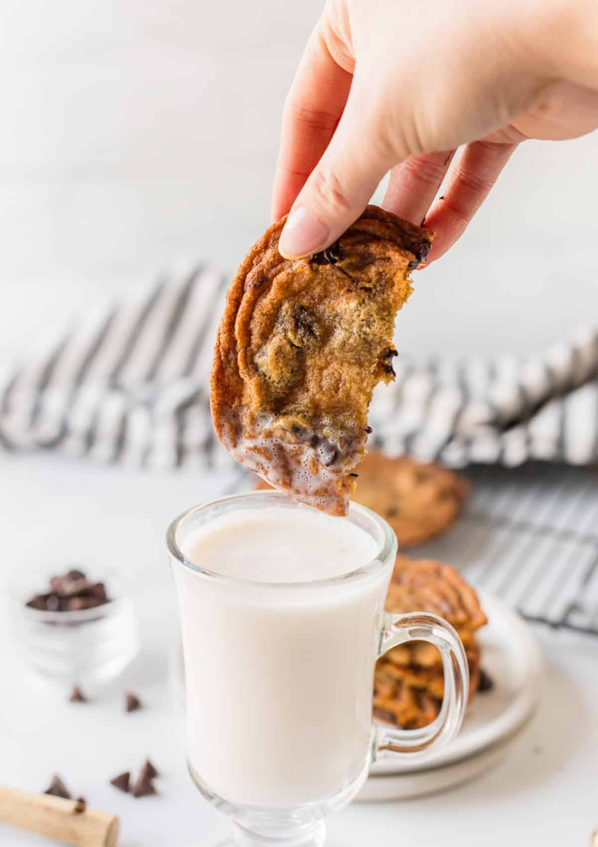 dipping a chocolate chip cookie into a glass of milk