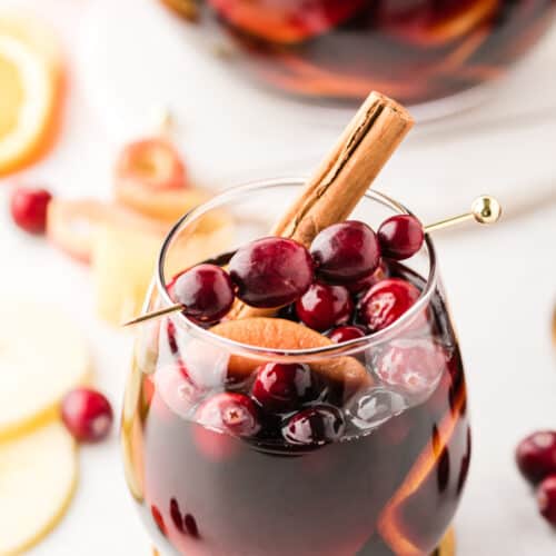 glass of apple cranberry sangria with cranberries and cinnamon garnish