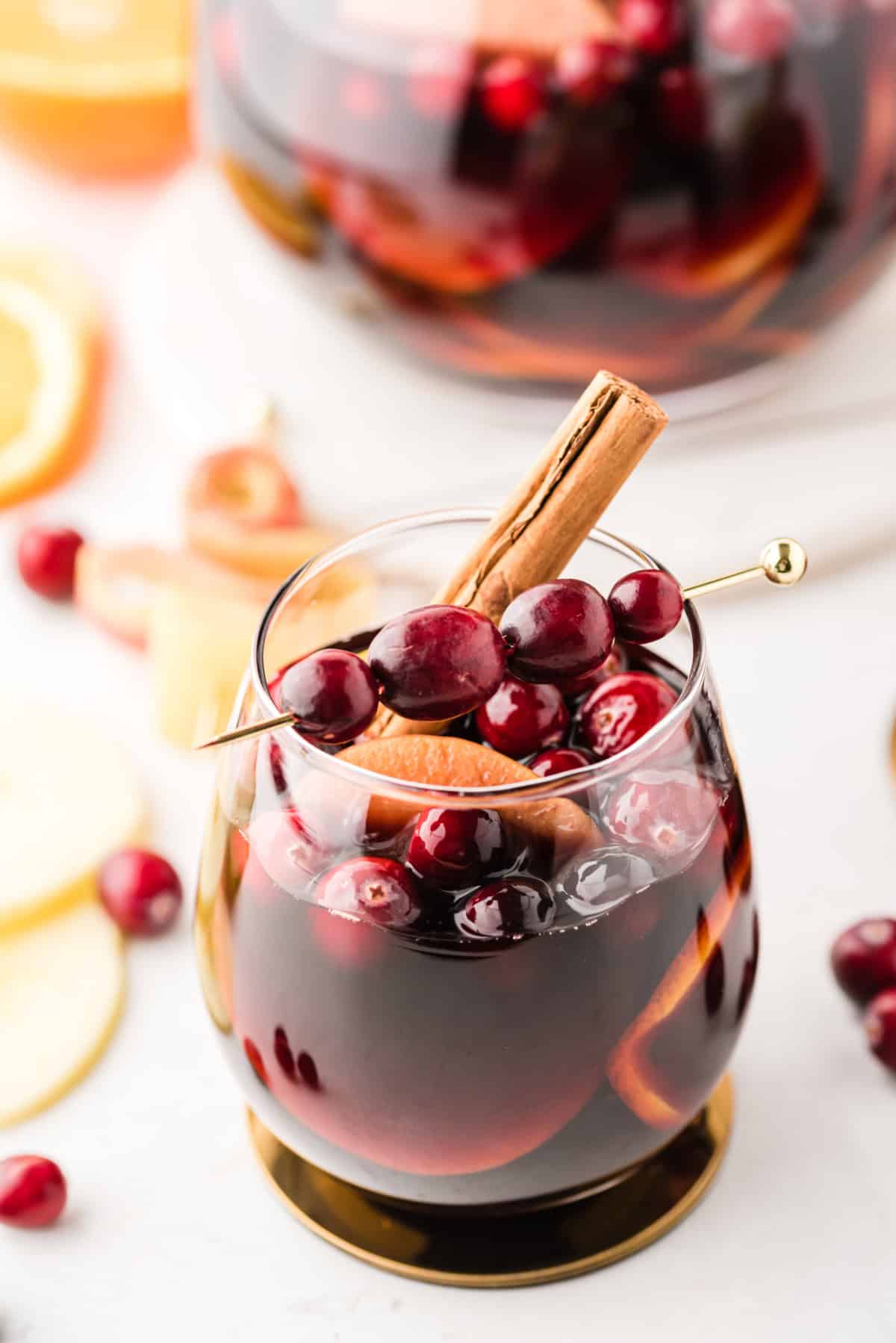 glass of apple cranberry sangria with cranberries and cinnamon garnish