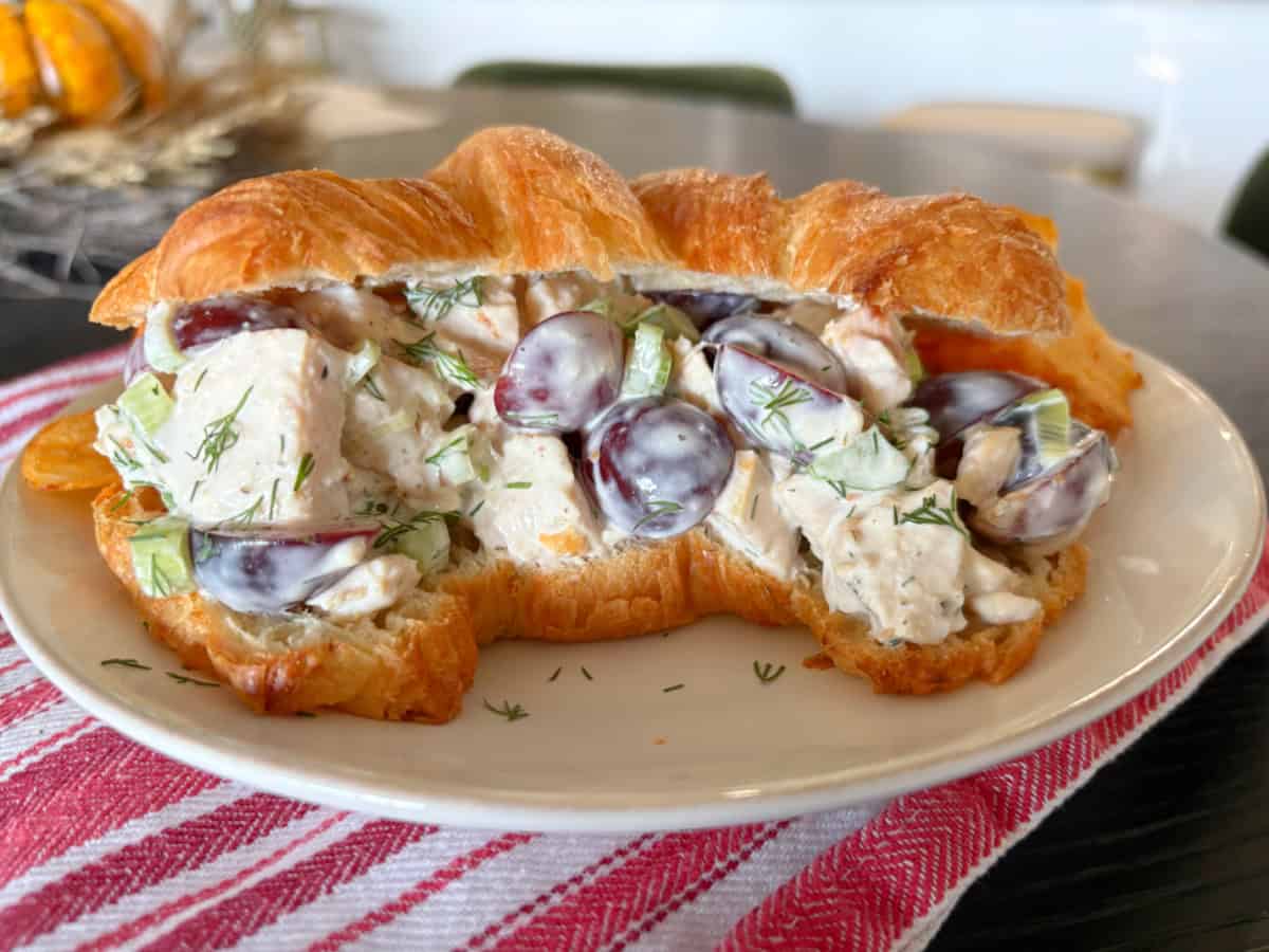 This creamy chicken salad from Pioneer Woman’s The Essential Recipes cookbook is filled with grapes, dill, and lemony dressing. A fresh, make-ahead lunch idea! chicken salad in a croissant