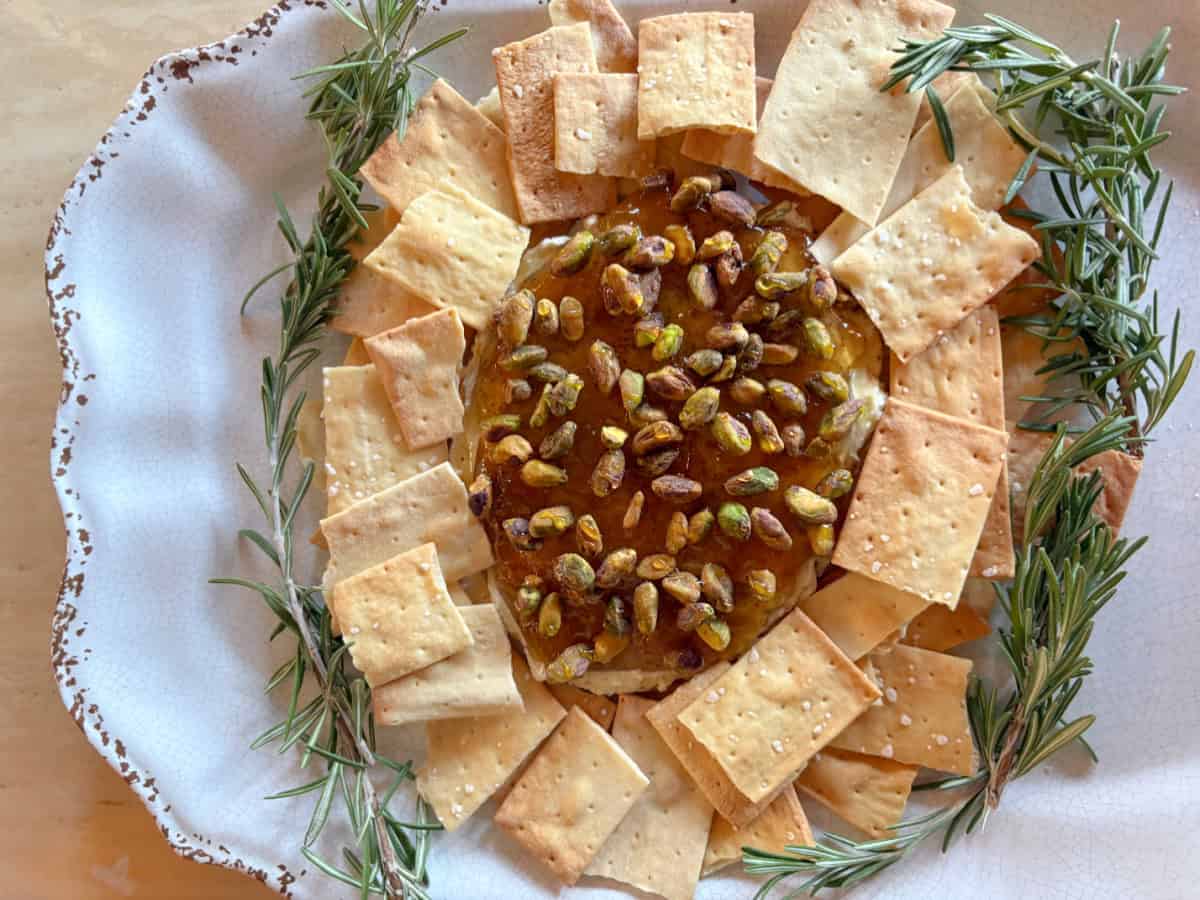 The easiest appetizer ever! Creamy Boursin topped with fig jam, pistachios, and hot honey. Sweet, salty, crunchy, and ready in minutes—perfect for parties! boursin cheese dip with crackers on platter