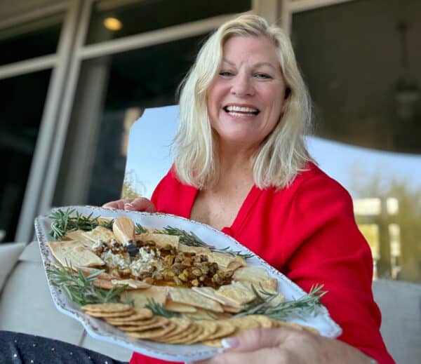 The easiest appetizer ever! Creamy Boursin topped with fig jam, pistachios, and hot honey. Sweet, salty, crunchy, and ready in minutes—perfect for parties! recipegirl holding platter of boursin cheese dip and crackers