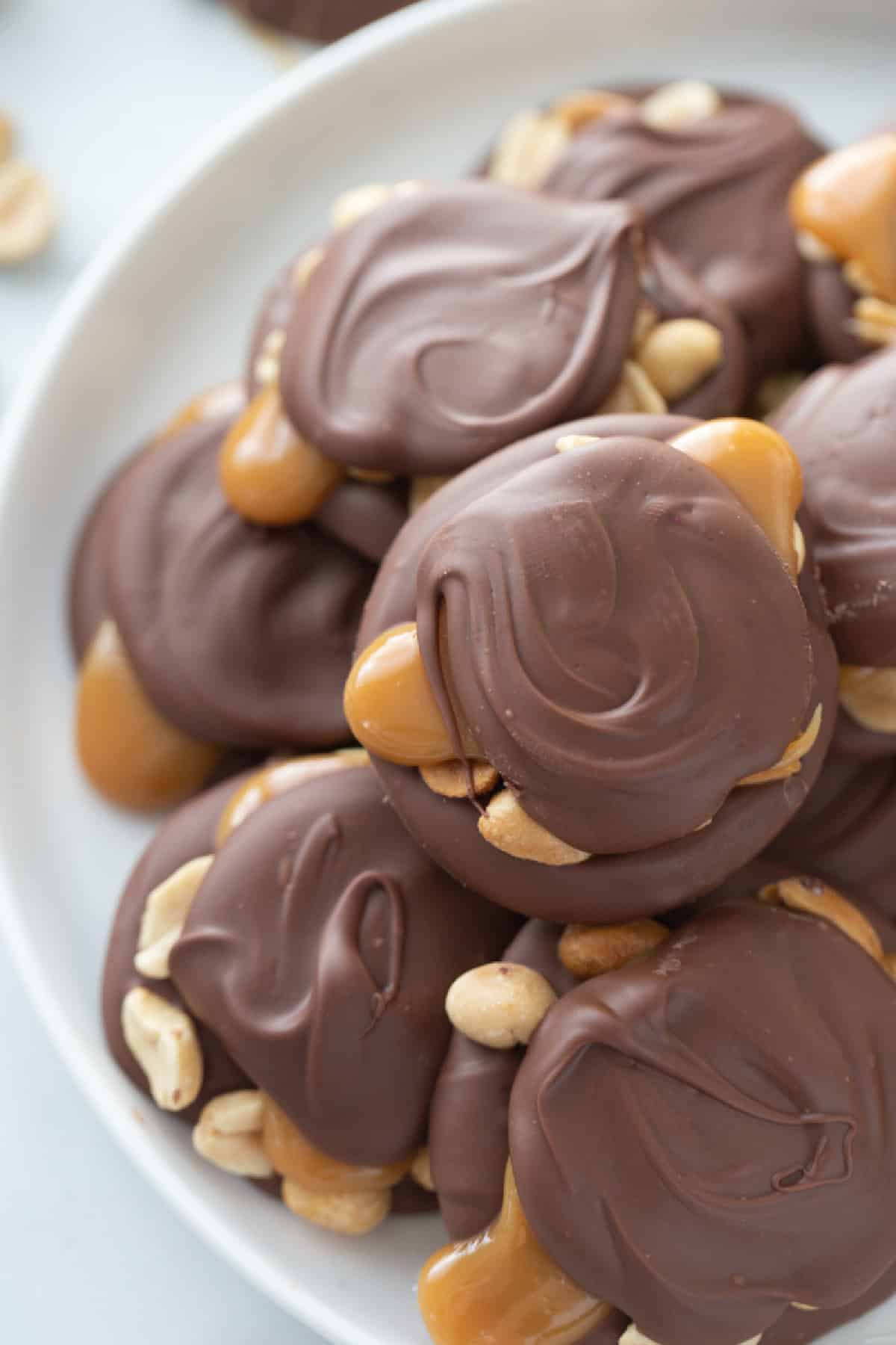 These Easy Caramel Peanut Clusters are layered with melted chocolate, roasted peanuts, and soft caramel—just like gourmet candy shop treats but so simple to make! chocolate caramel peanut clusters on a platter