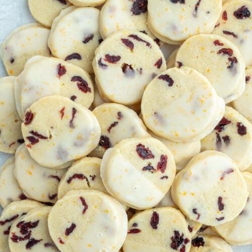 many cranberry orange cookies that have been dipped in glaze