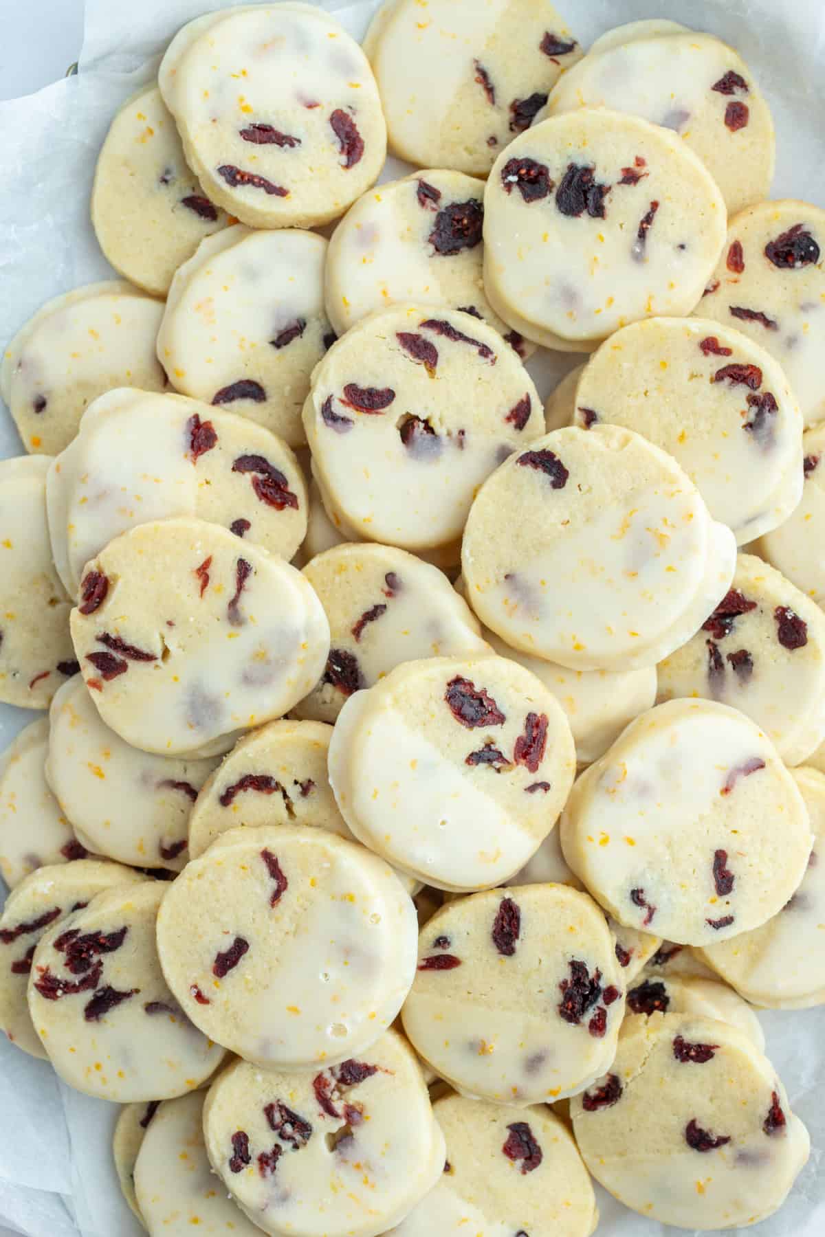 Bright, buttery Cranberry Orange Cookies loaded with dried cranberries and fresh orange zest, dipped in a sweet citrus glaze. A gorgeous slice-and-bake cookie for the holidays! many cranberry orange cookies that have been dipped in glaze