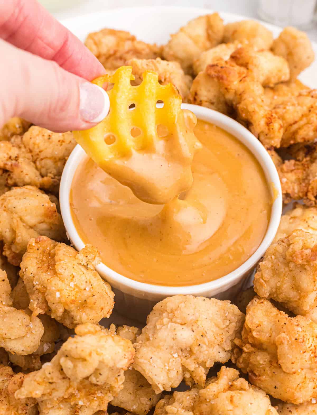 dipping a waffle fry into chick-fil-a sauce