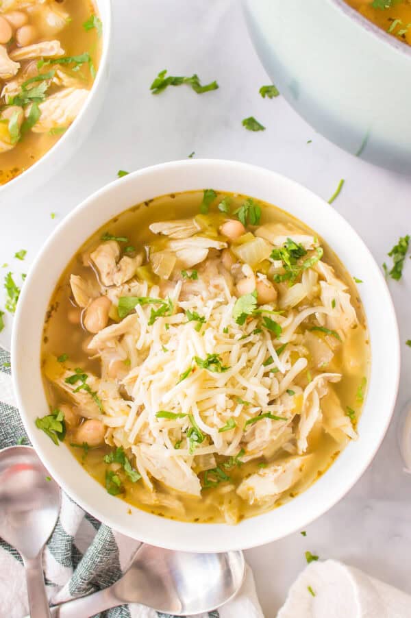 bowl of white bean chicken chili topped with cheese and cilantro