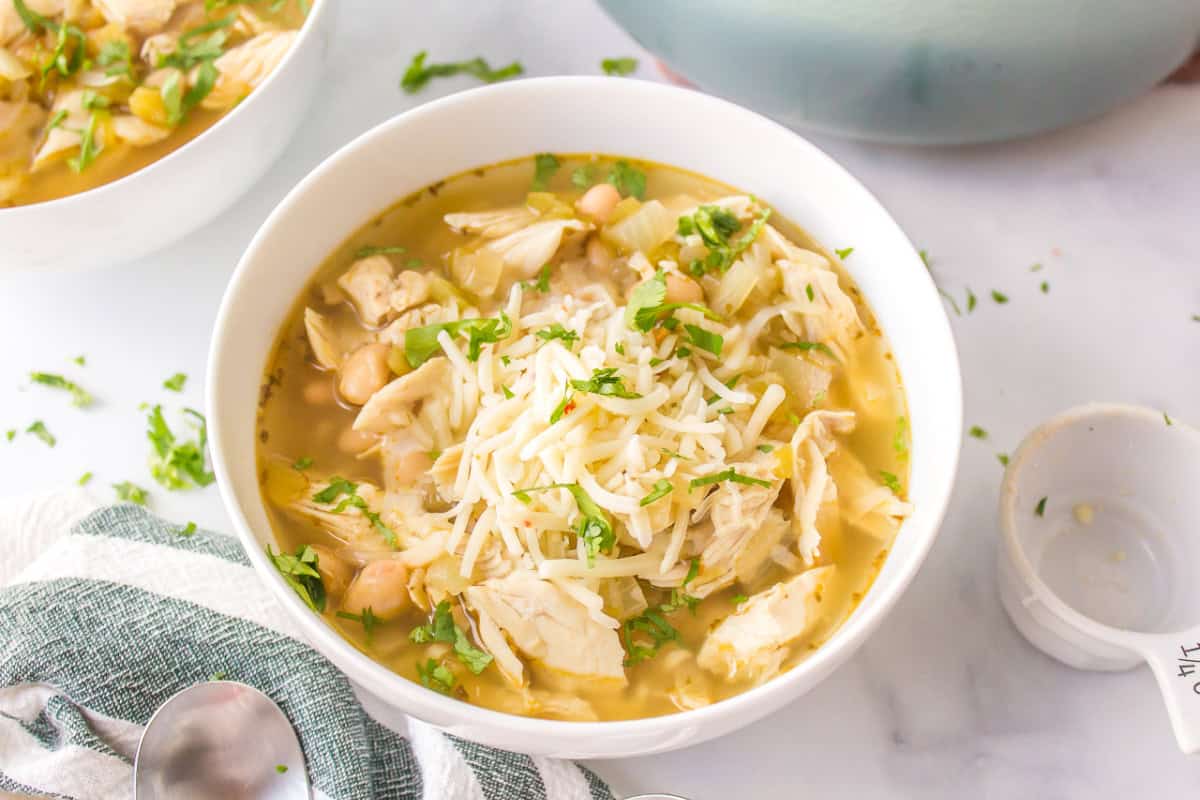 white bowl of white bean chicken chili topped with cheese