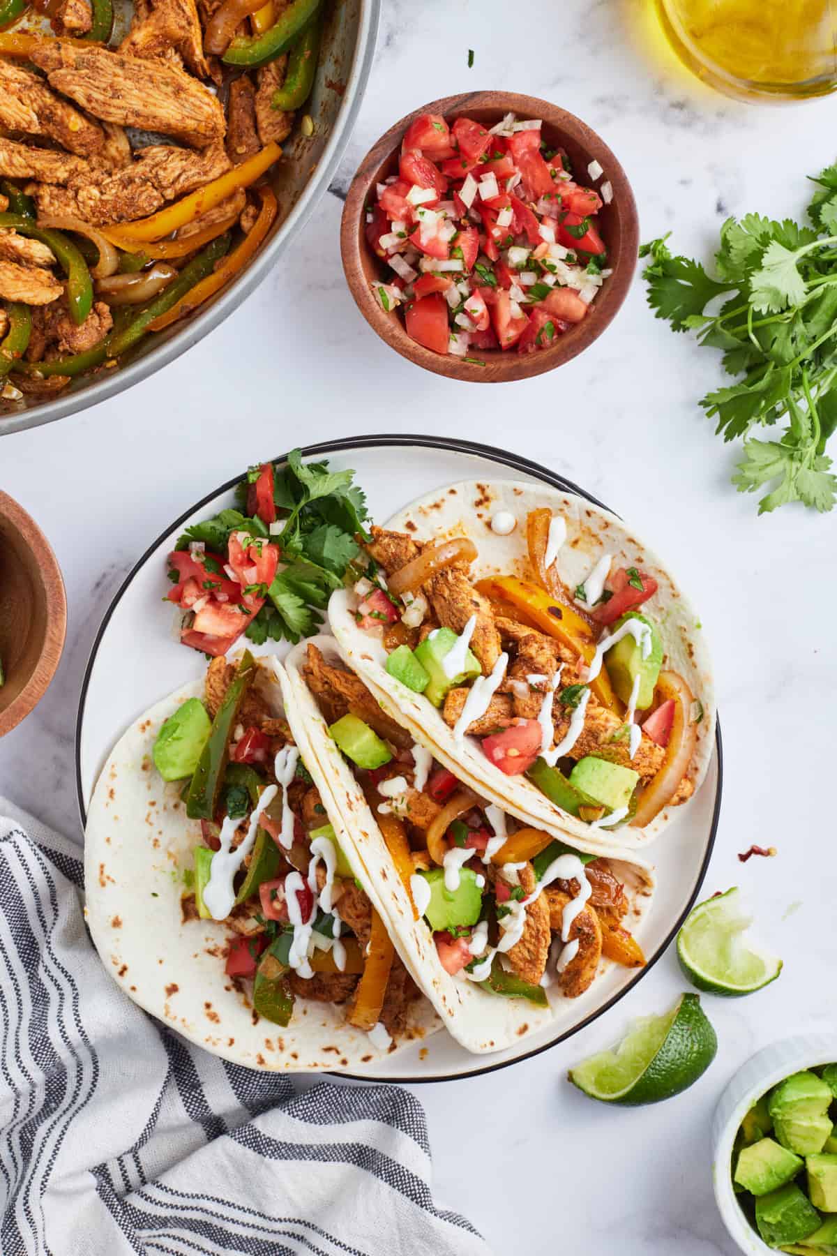overhead shot of three chicken fajitas on plate wrapped into tortillas