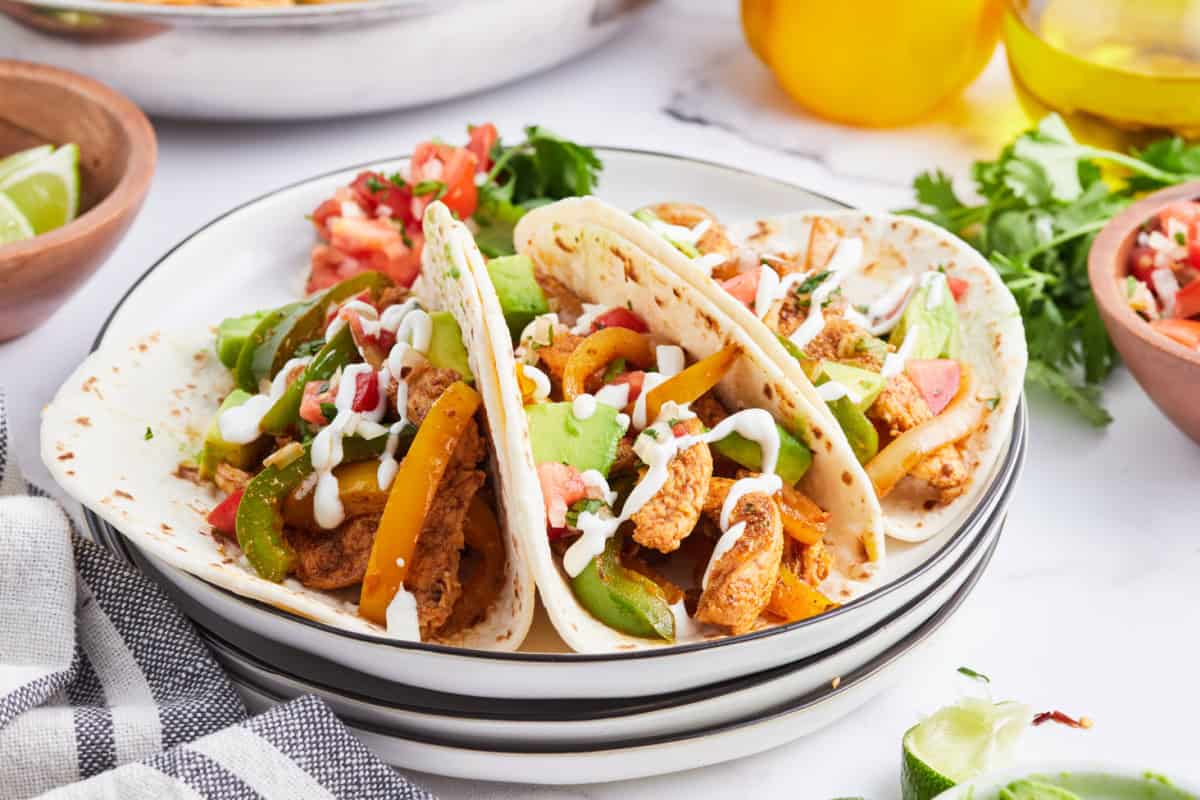 chicken fajitas wrapped into tortillas on a plate