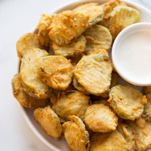 deep fried pickles on a platter with sauce