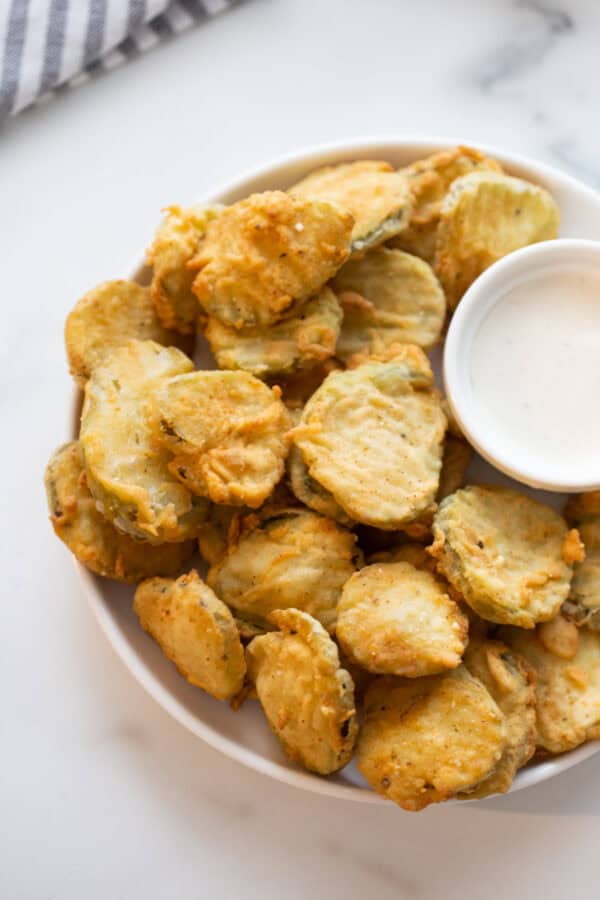 deep fried pickles on a platter with sauce