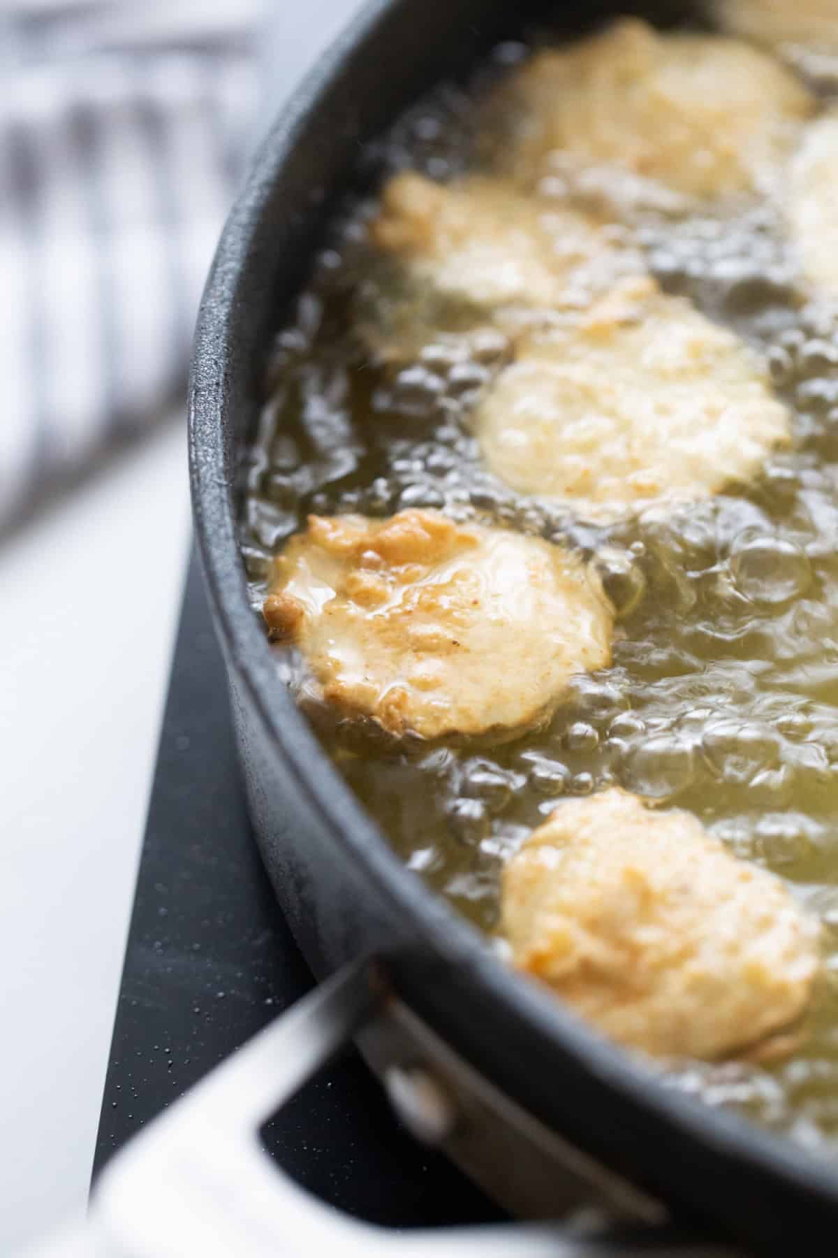 Deep Fried Pickles are crispy, golden and totally addictive. An easy appetizer recipe perfect for game day or snacking. pickles frying in a pan