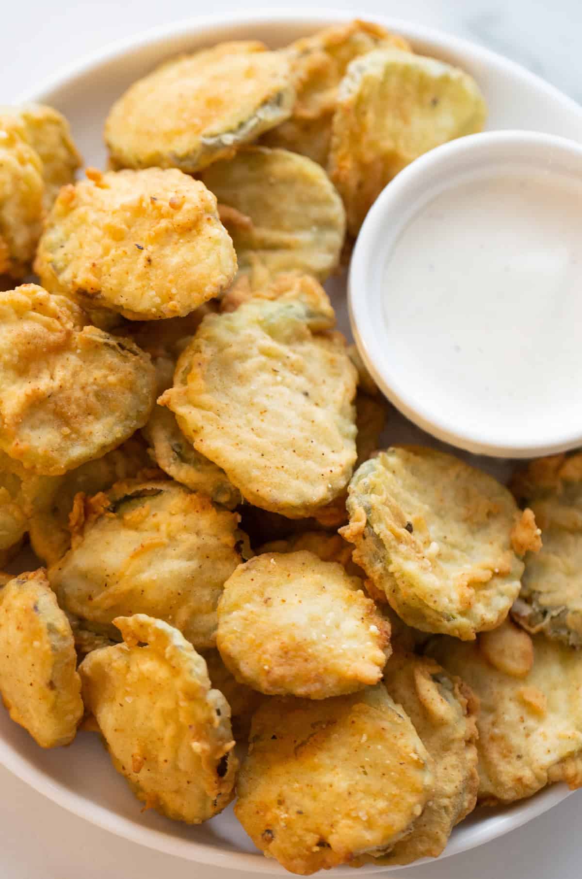 Deep Fried Pickles are crispy, golden and totally addictive. An easy appetizer recipe perfect for game day or snacking. deep fried pickles on a platter with a bowl of sauce