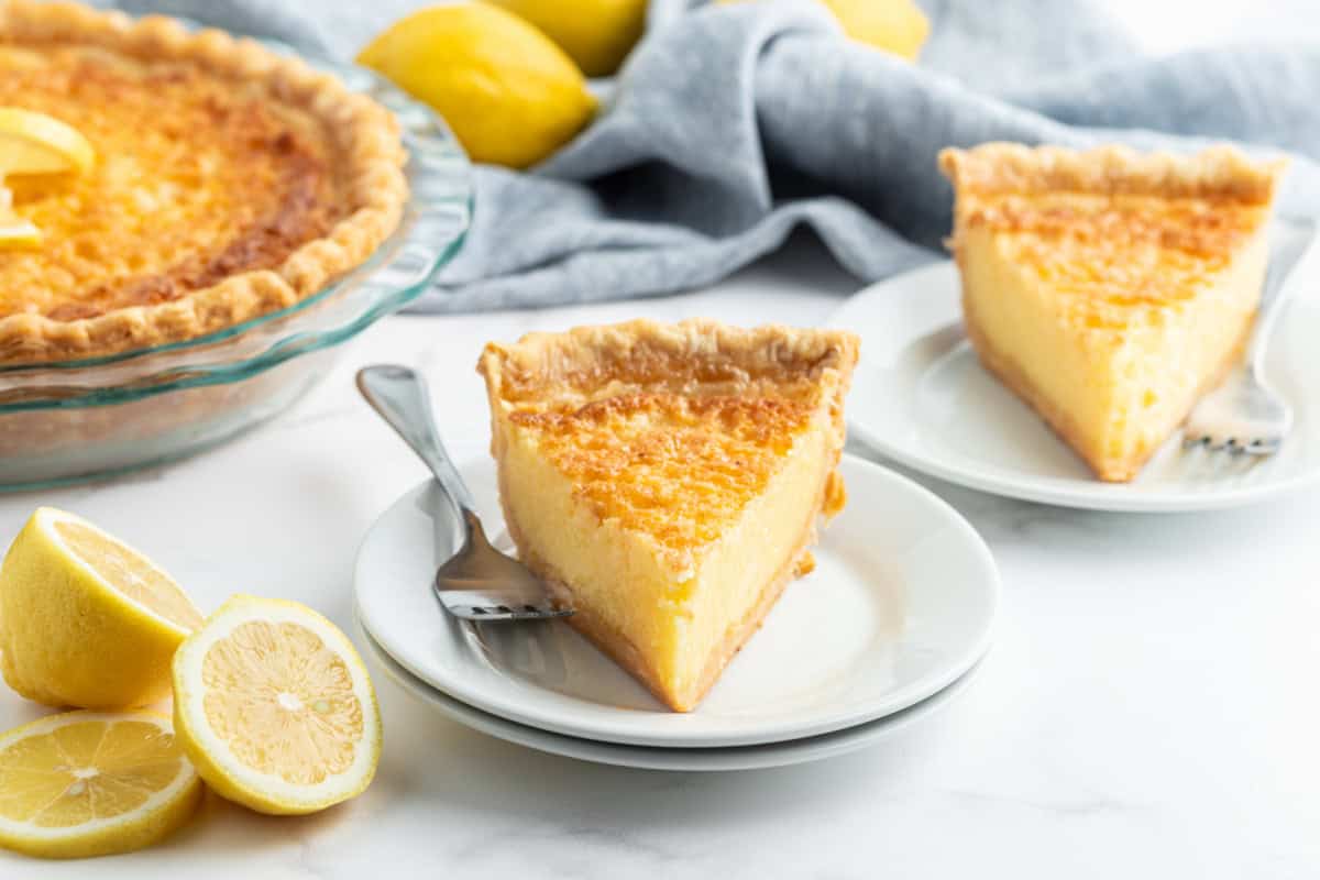 Classic Lemon Custard Pie (also known as Lemon Chess Pie) with a sweet, tangy lemon filling and flaky crust. slice of lemon custard pie on a plate