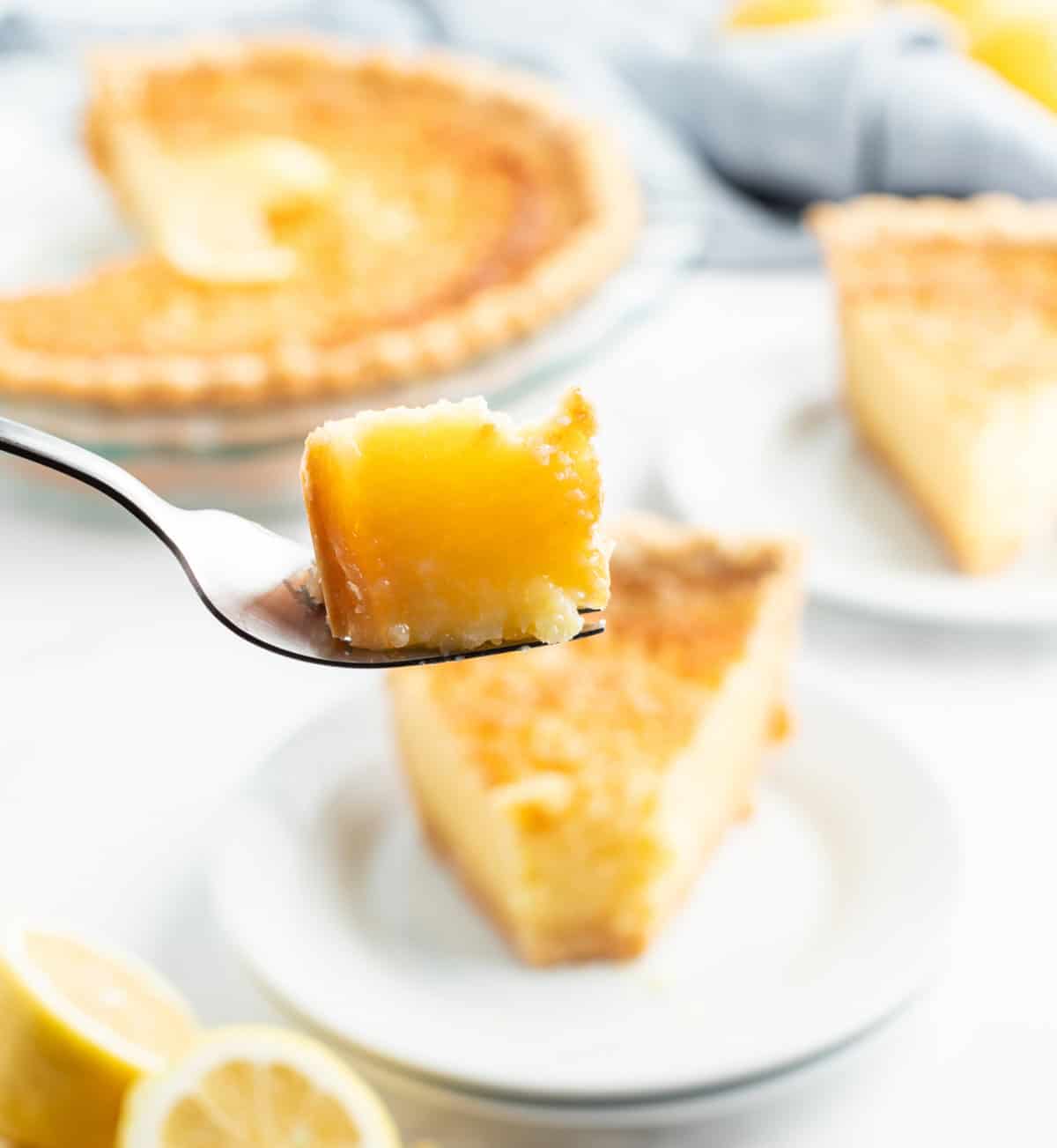Classic Lemon Custard Pie (also known as Lemon Chess Pie) with a sweet, tangy lemon filling and flaky crust. fork full of lemon custard pie