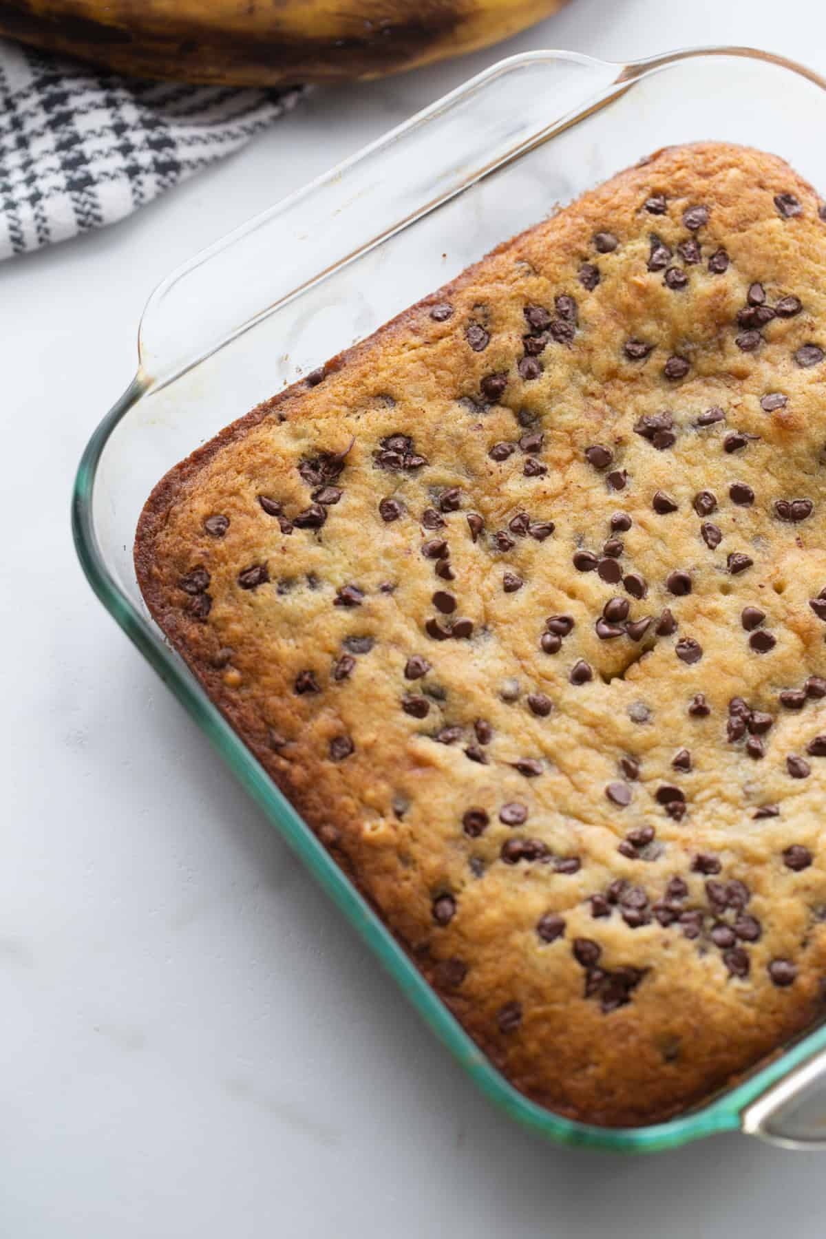 Chocolate chip banana snack cake that’s soft, moist and easy to make. A simple one-pan dessert everyone will love! chocolate chip banana snack cake in a pan